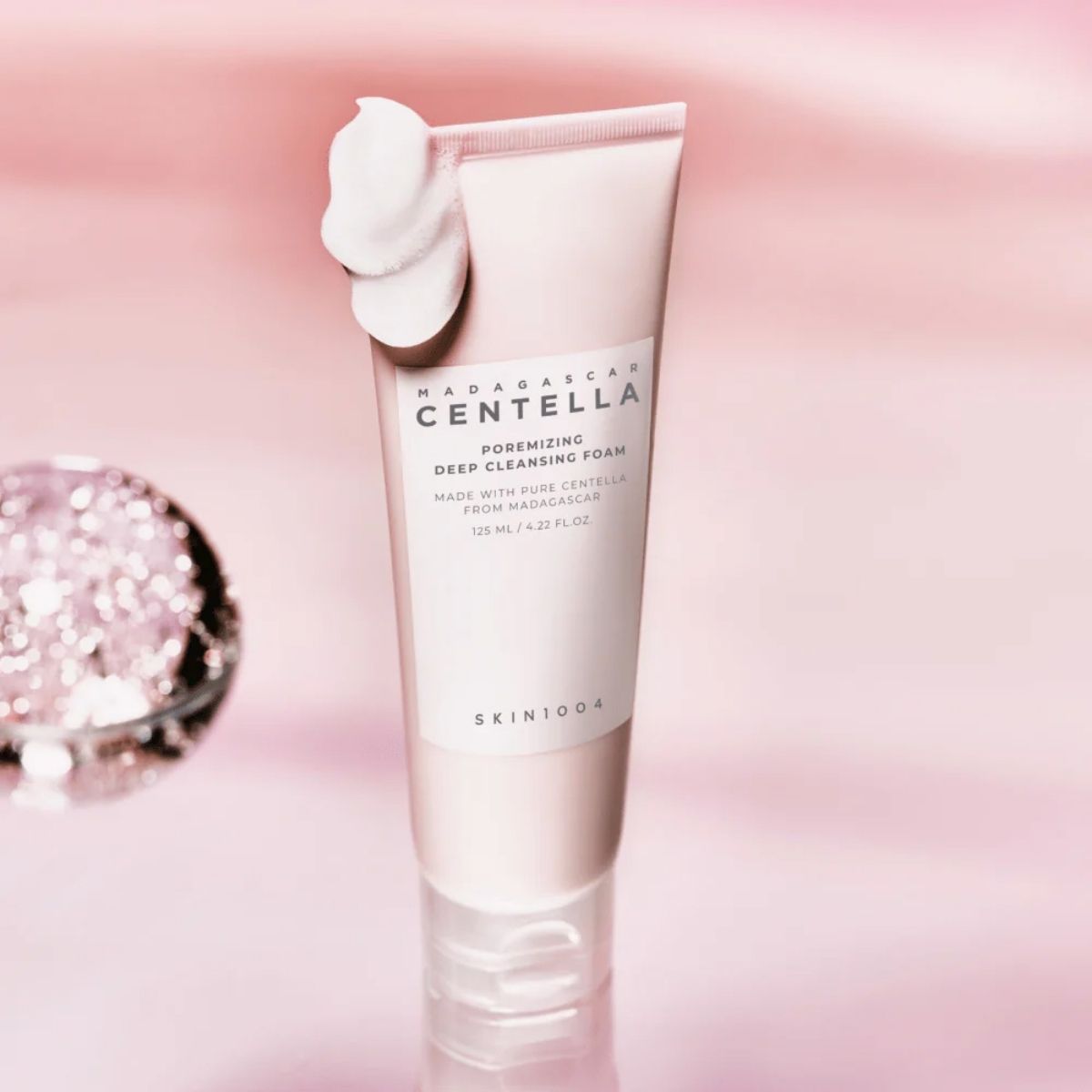SKIN1004 Madagascar Centella Poremizing Deep Cleansing Foam met rijk schuim op een roze achtergrond