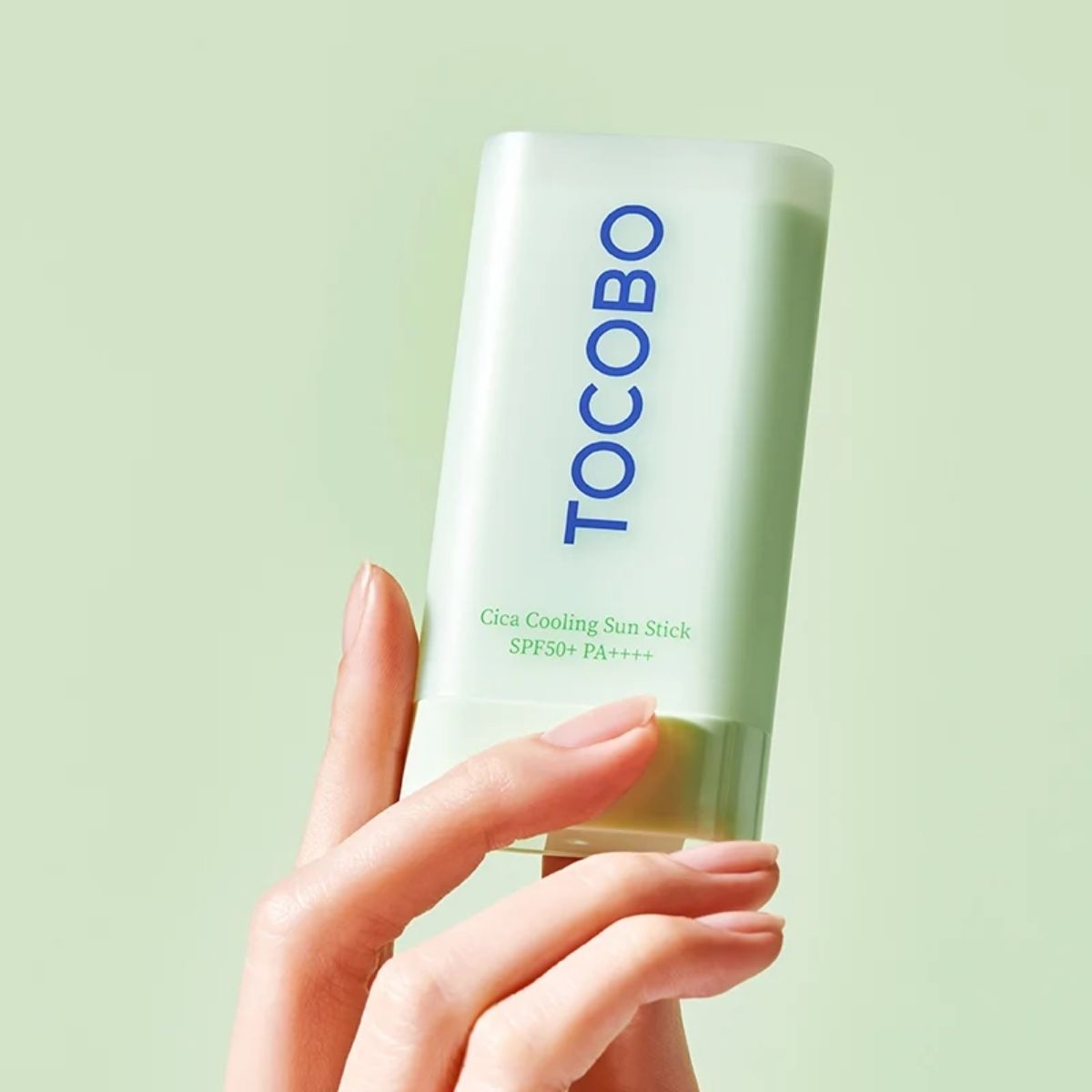 TOCOBO Cica Cooling Sun Stick SPF50+ in de hand tegen een lichtgroene achtergrond.